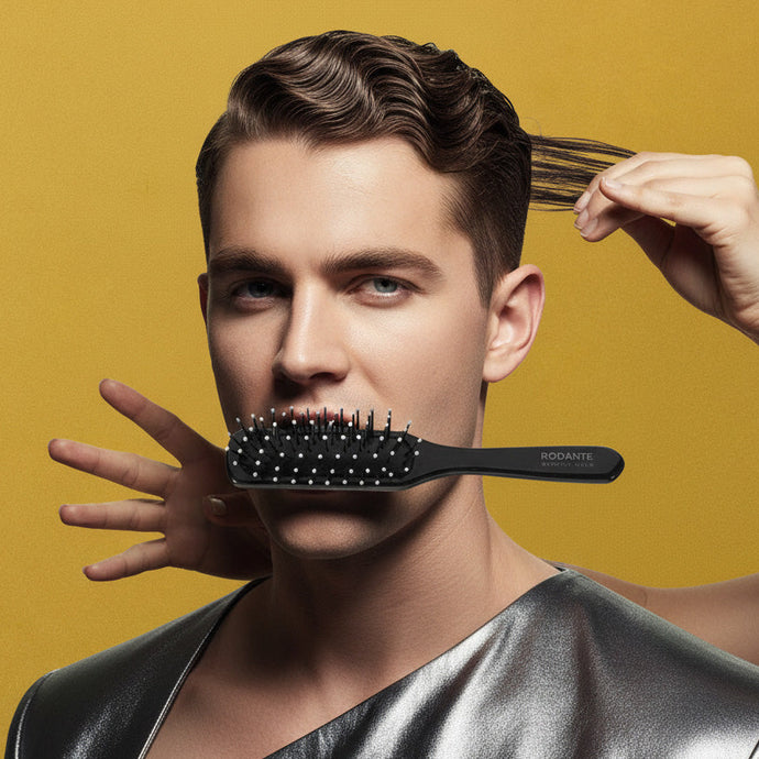 Man with styled hair, holding a hairbrush, against a yellow background